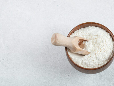 A wooden bowl of flour and wooden spoon . High quality photo